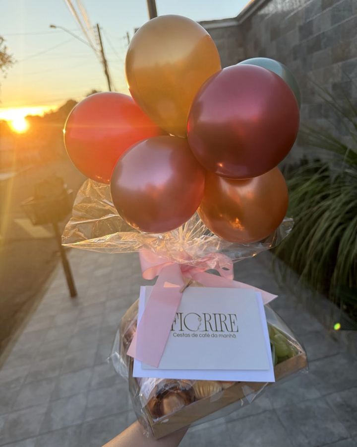 Cesta com balões sendo entregue ao pôr do sol